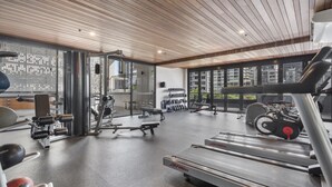 A modern gym with cardio equipment, weight machines, and a bench. - Central South Brisbane 2-Bed with Stunning Views (South Brisbane)
