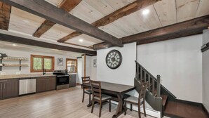A spacious kitchen with modern appliances, a dining area with a wooden table and chairs, and a staircase leading to an upper level. - NEW! NH Getaway l HOT TUB l NearWhiteMountain (Campton)