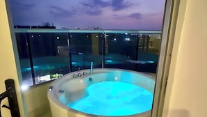 Un jacuzzi en un balcón con vista a la ciudad al atardecer.