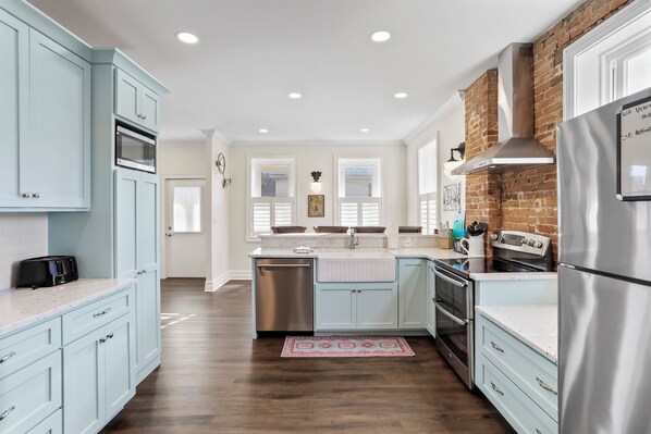 A modern kitchen with light blue cabinets, stainless steel appliances, and a brick accent wall. - Clever Rabbit- Raystown Lake-Seven Points- Aunt Susies (Hesston)