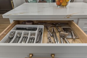 A drawer with neatly organized kitchen utensils including spoons, forks, knives, and a grater. - 2025 Luxury Townhome with Rooftop near Medical Center/Downtown Houston (Houston)