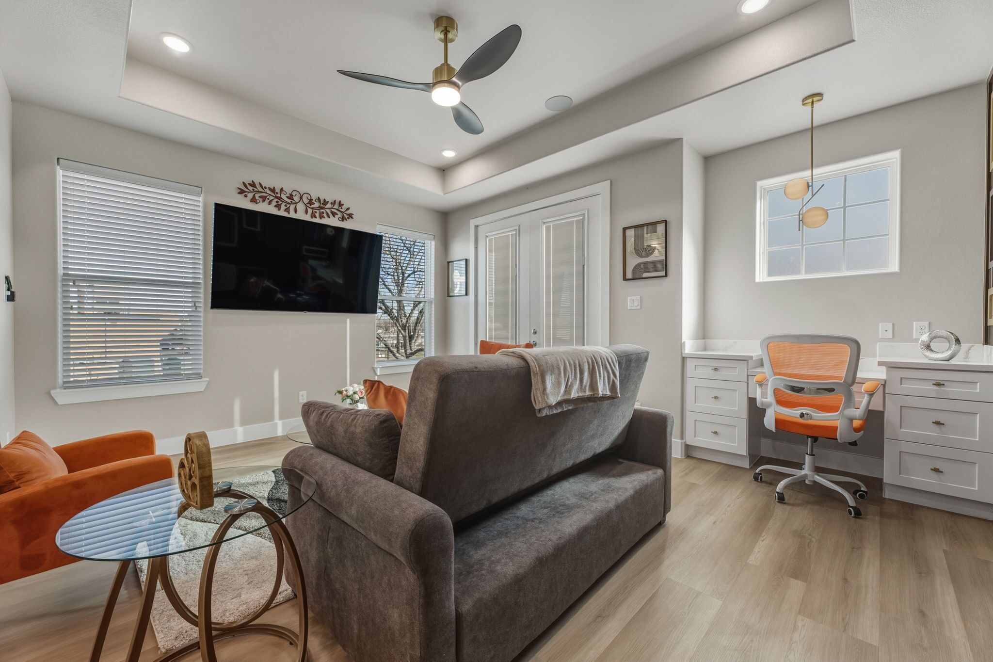 A modern living room with a grey sofa, orange armchair, and a glass coffee table.
