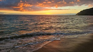 Une plage avec des vagues et un coucher de soleil.