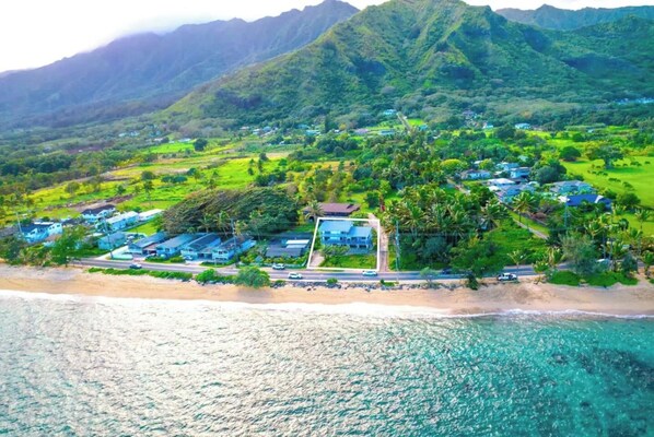 Une vue aérienne d’une station balnéaire comprenant plusieurs bâtiments, une plage et une végétation luxuriante.