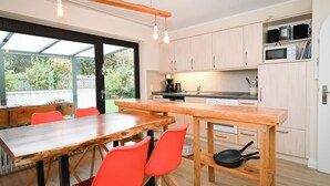 Una cocina moderna con armarios de madera, una mesa de comedor de madera y sillas color naranja brillante.