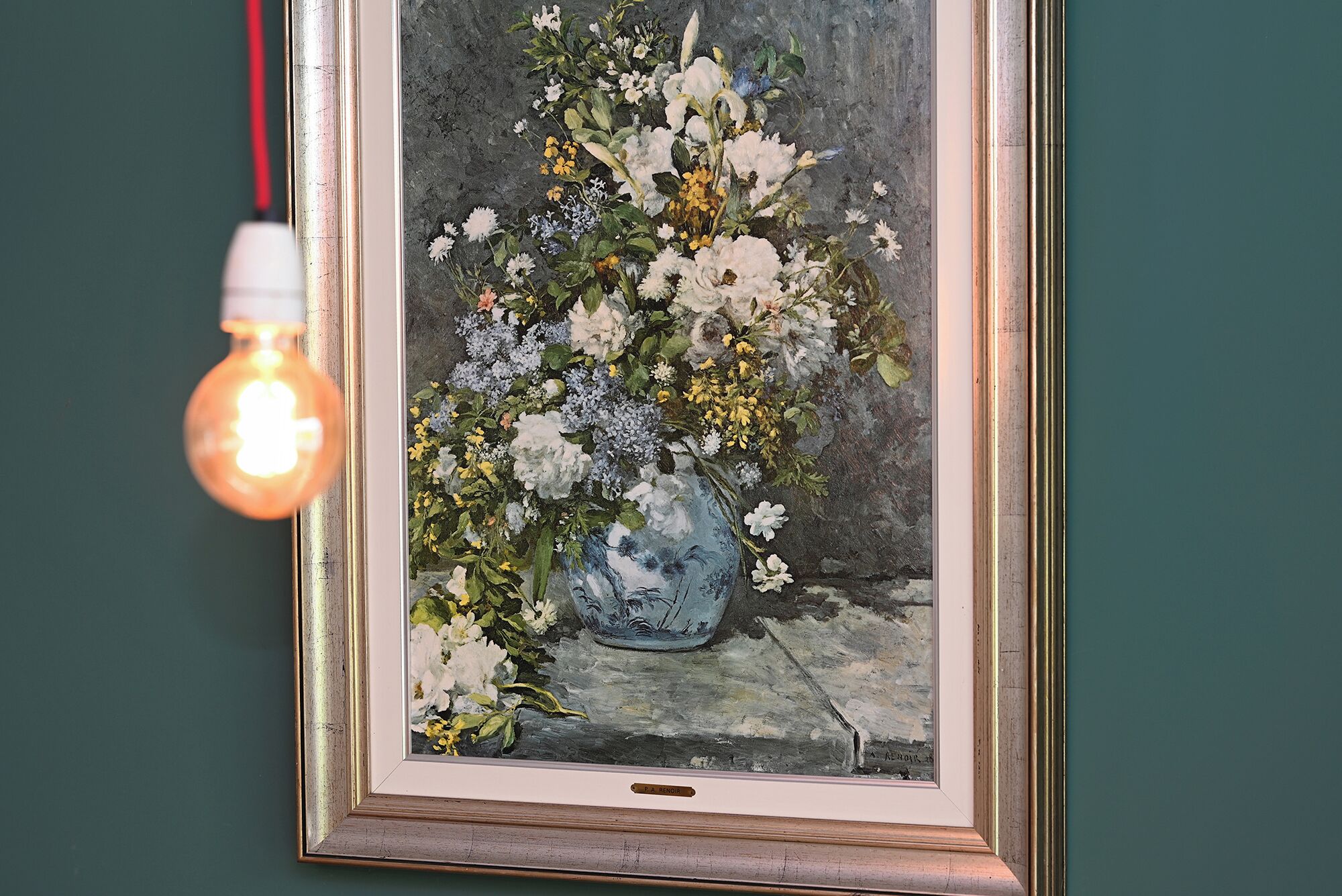 A framed painting of a floral arrangement on a wall.