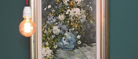 A framed painting of a floral arrangement on a wall.