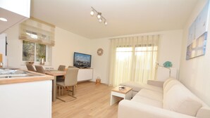 A modern living room with a sofa, dining table, and TV. - Watthof apartment 11<br>Modern apartment in a quiet location with access to the sea (Stinteck)