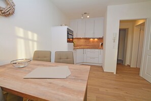 A compact kitchen with white cabinets, a wooden countertop, and a dining area with a table and chairs. - Watthof apartment 12<br>Cozy apartment in a quiet location & entrance to the sea time (Stinteck)