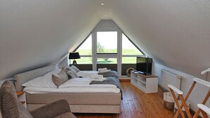 Une chambre avec un grand lit, une télévision et une vue sur l’extérieur.