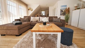 Un salon moderne avec un canapé d’angle, une table basse en bois et un tapis moelleux.
