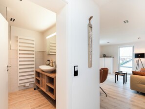 A modern, well-lit living room with a large window, a sofa, a coffee table, and a floor lamp. - Inseltörn apartment 10 (Büsum)