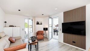 Ein modernes Wohnzimmer mit einer Couch, einem Couchtisch und einem an einer Holzwand montierten Fernseher.