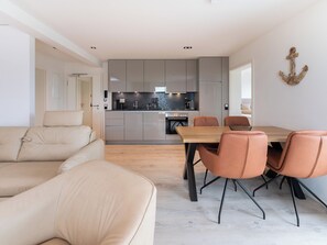 Eine moderne Küche mit grauen Schränken, einem Holztisch und orangefarbenen Stühlen.