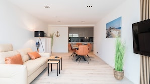 A modern living room with a sofa, coffee table, and dining area. - Inseltörn apartment 3 <br>Spacious apartment for 6 people & entry to the swimming pool (Büsum)