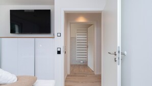 A bedroom with a bed, a television mounted on the wall, and a door leading to a hallway. - Inseltörn apartment 3 <br>Spacious apartment for 6 people & entry to the swimming pool (Büsum)