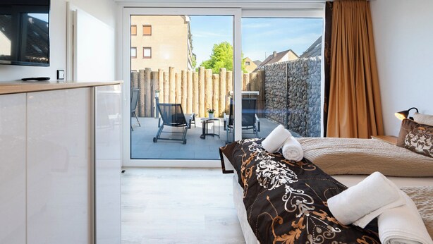 A modern hotel room with a large bed, a desk, and a view of the outdoor area. - Inseltörn apartment 3 <br>Spacious apartment for 6 people & entry to the swimming pool (Büsum)