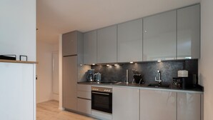 A modern kitchen with grey cabinets, a built-in oven, and a coffee maker. - Inseltörn apartment 6 - Comfortable for 6 people & admission to the swimming pool included. (Büsum)