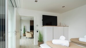 A modern hotel room with a large bed, a television mounted on the wall, and a view into the hallway. - Inseltörn apartment 6 - Comfortable for 6 people & admission to the swimming pool included. (Büsum)