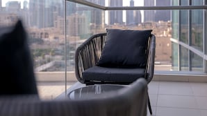 A balcony with a wicker chair and a glass table, overlooking a cityscape with tall buildings. - Stayshort - Luxury 2 Bedroom in Downtown That Sleeps 4 With Balcony (Dubai)
