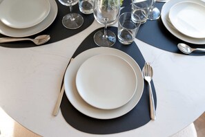 Een tafel gedekt met borden, bestek en glazen, geplaatst op een witte tafel met een zwarte placemat.