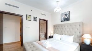 A modern hotel room with a large bed, a headboard, bedside tables, and a bathroom visible through an open door. - Stayshort - Luxury 2 Bedroom in Downtown That Sleeps 4 With Balcony (Dubai)