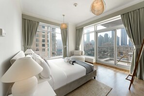 A modern hotel room with a large bed, a city view, and a balcony with a chair. - Stayshort - Luxury 2 Bedroom in Downtown That Sleeps 4 With Balcony (Dubai)