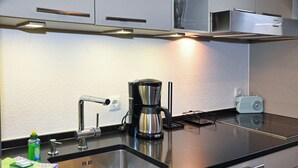 Une cuisine moderne équipée d’un évier en acier inoxydable, d’une machine à café et d’une bouilloire.