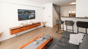 Un soggiorno moderno con un tavolino consolle in legno, un divano grigio e una TV a parete.