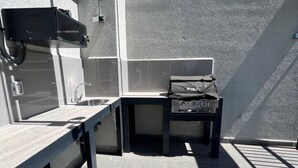 Eine moderne Außenpatio mit integriertem Grill, einem kleinen Tisch und einer Bank.
