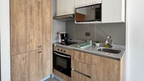 Eine moderne Küche mit Holzschränken, einem Einbauofen, einer Mikrowelle und einem Spülbecken.