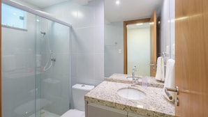 A modern bathroom with a glass-enclosed shower, a sink with a mirror, and a toilet. - Beachfront Paradise in Condo w/ Pool in Itacimirim - Rsvs (Camaçari)