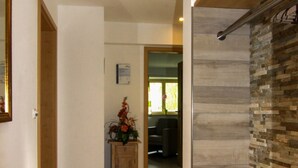Um corredor com piso de madeira, parede de destaque em pedra e um vigamento de madeira no teto.