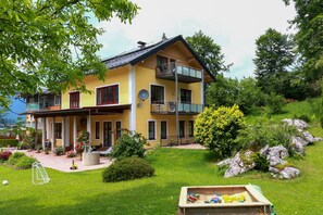 Ein zweistöckiges Haus mit Balkon, umgeben von einem gepflegten Garten und einem kleinen Teich.