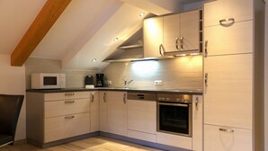Uma cozinha moderna com eletrodomésticos embutidos, vigas de madeira e painel de azulejos.