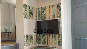 Une pièce avec un téléviseur fixé au mur, un papier peint à motifs et une petite boîte décorative.