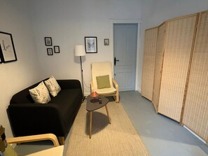 A living room with a black sofa, a small table with a lamp, a chair, and a wardrobe. - Cozy apartment in Cazorla with Wi-Fi and air conditioning (Cazorla)