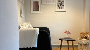 Une pièce confortable avec un lit, une petite table sur laquelle se trouve une lampe, et un ours en peluche.