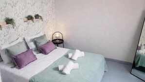Une chambre à coucher avec un lit, des oreillers, une table de chevet avec une lampe et un miroir.