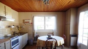 Eine Küche mit Holzbalkendecke, einem Esstisch mit Stühlen und einem Fenster, das für natürliches Licht sorgt.