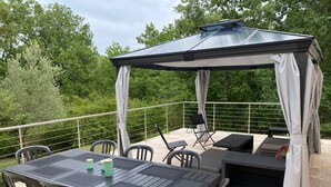 A covered outdoor patio with a table and chairs, a seating area, and a pergola. - 4-bed house with garden near Cahors, smart TV & Wii, peaceful and comfortable (Pradines)