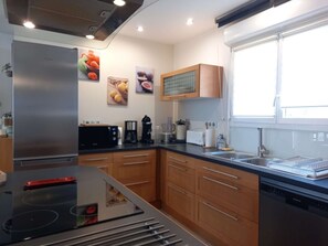 Una cocina moderna con estufa integrada, lavavajillas, armarios de madera y ventana que proporciona luz natural.