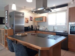Una cocina moderna con una isla central, electrodomésticos de acero inoxidable y armarios de madera.