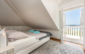 A bedroom with a bed, a nightstand, a window with a view of the sea, and a balcony. - Beautiful apartment in Biograd (Biograd)