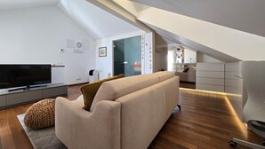 Eine moderne Lofts-Wohnung mit großem Fernseher, einer Couch und Holzboden.