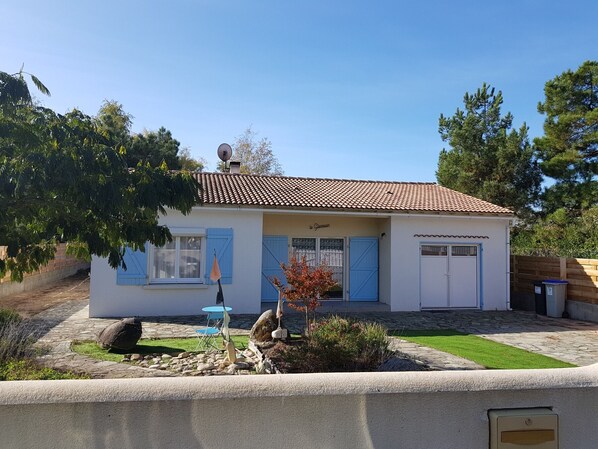 A two-story building with a tiled roof, a small garden with rocks and plants, and a blue door. - Renovated house near beach, with parking, ideal for 4/6 people (La Tranche-sur-Mer)