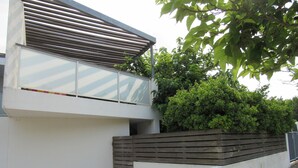 Un bâtiment moderne avec une façade blanche, un toit incliné et une clôture en bois.