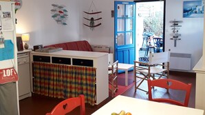 Een kleine keuken met een eethoek, een blauwe deur en uitzicht op buiten.