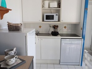 Eine kompakte Küche mit weißen Schränken, einer Mikrowelle, einem Toaster und einem Geschirrspüler.