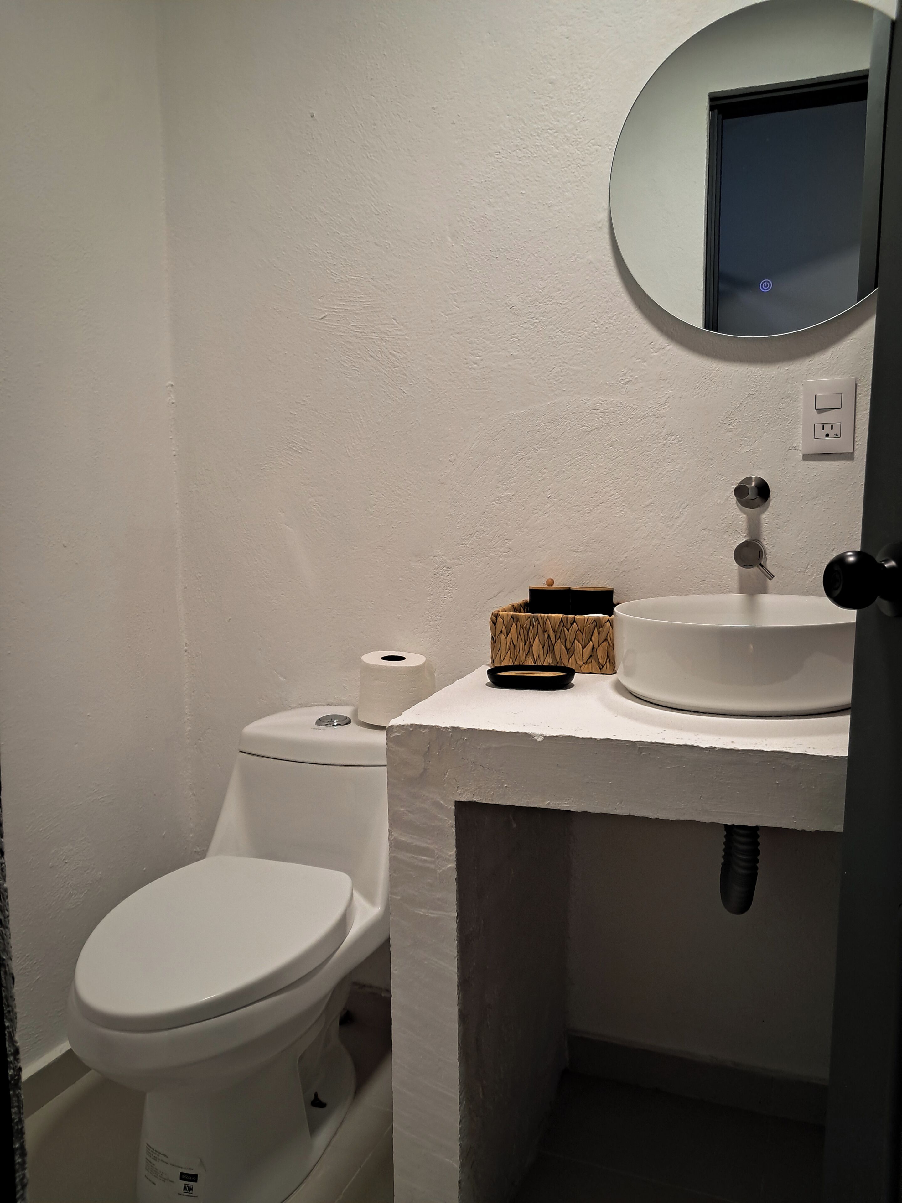 A small bathroom with a toilet, a sink, and a mirror.